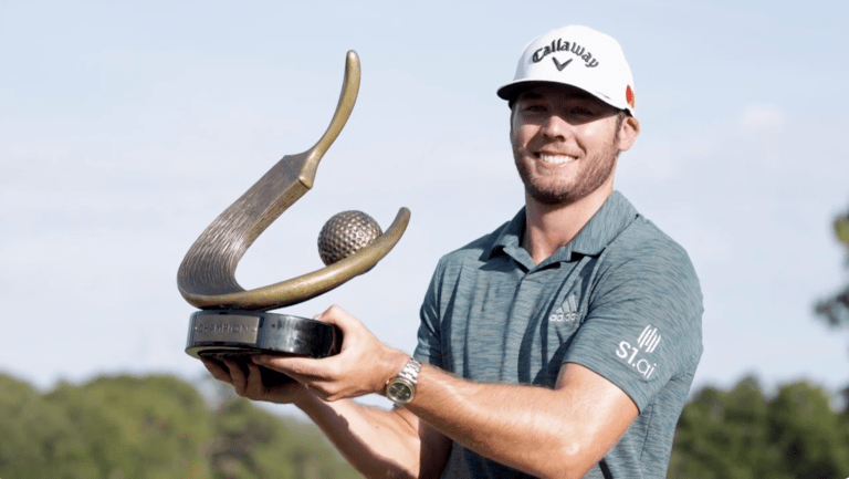 Sam Burns celebrates with a trophy, featured in the Memorial Round 2 recap for his impressive 7-under round.